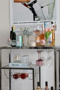 Aesthetic bar cart College apartment decor Silver bar cart from Amazon 818 Candles Prada Bar cart display Bar cart decor Living room decor Minimalist apartment Living room designs Room ideas Home decor