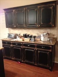 Black cabinets with faux distressing. Used 3 different colors of flat paint to create this super distressed look. Love the dingy black. DIY success.