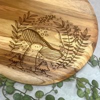 Transform your culinary creations into works of art with our unique Cutting Board. Crafted with precision by a local artist and featuring a laser engraved mushroom design, this multi-purpose board is perfect for all of your cutting, cheese-serving, and display needs. Make an impression with this sophisticated, elegant, and tasteful addition to your kitchen.