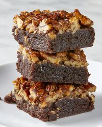 Head on view of a stack of three brownie slices on a white plate.