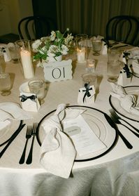 The perfect wedding table, with personalized place settings. Black-and-white chargers, black utensils. Favors. Candles, and flowers.