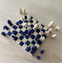 This 32-piece chess set is handcrafted using clay and imprints from seashells and coral from her personal collections and travels from Miami Beach, Italy and Greece. Each piece is hand-glazed. Blue pieces have a smooth finish, while cream pieces retain a rough, almost sandy texture.  The organic design and process means each one is completely unique. Materials: Clay Dimensions: Board is 8" x 8" Pieces range between 1"- 2" in size. Care: Wipe gently with a soft, dry cloth. *Made to order, please