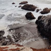 An aesthetic photograph of the beach against a cliffside.