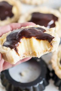 These delicious Boston Cream Pie Cookies are handheld versions of the classic Boston Cream Pie dessert! The soft vanilla cookie base is made in a tart or cup shape to hold the rich vanilla pastry cream, then topped with a rich dark chocolate ganache, giving them an authentic taste just like the original cake! #bostoncreampiecookies #cookies #bostoncreampie