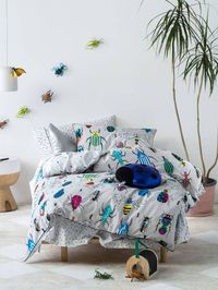 Bugs and beetles of all shapes and sizes, Insectarium features friendly little critters that will make a vibrant statement in royal blue, yellow, pink and emerald on on a grey background. Reversing to a cool ant print, the quilt is trimmed with cord piping. Creative kids bedding