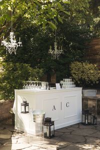 Old Hollywood Glamour Small Backyard Wedding. Self serve bar. DIY wedding bar. White bar with black monogram initials and chandeliers hanging from trees. Backyward wedding bar