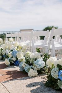 Beautifully decorated outdoor wedding aisle featuring white and blue hydrangeas, creating a serene and elegant atmosphere perfect for a romantic ceremony. #OutdoorWedding #WeddingAisle #Hydrangeas #WeddingFlowers #WeddingDecor #ElegantWedding #BlueHydrangeas #WhiteHydrangeas