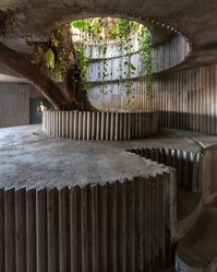 Lina Bo Bardi’s Coaty, located on Ladeira da Misericórdia in Salvador, Brazil, was part of her visionary plan to revitalize the area in the 1980s. The structure, designed in collaboration with João Filgueiras Lima, was a bold experiment that integrated a restaurant into the natural landscape, with its most striking feature being the tree growing through the roof. The folded concrete walls, still standing today, were created to stabilize the decaying buildings around them. Although the area h...