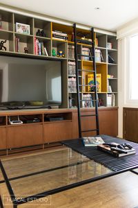 Modern family room | Walnut wood, lacquered mustard yellow and grey bookcase / entertainment center with sliding ladder. Main focus was to display comic collection and double as  storage space.  | Mexico City #HuacalEstudio #Bookcase #Comics #WalnutWood #Ladder