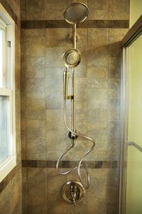 AFTER: A rejuvenated shower features a calming earth-tone palette and a stylish brushed nickel showerhead. Learn more about how you too can easily update your bathroom with our helpful tips.