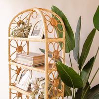 Give your plants, books and treasures a place to live with this rattan daisy shelf. Made from natural materials, this arching shelf features rattan daisies on both sides and ample space to display your favorite things. Each sold separately. Available in sizes Small & Large.