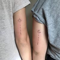 Matching sun and crescent moon tattoos on upper arms