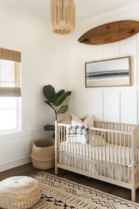 nursery with white walls and a wood crib with surf board hanging over crib