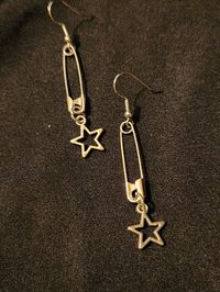 Safety pins on earring hooks, accented with open (hollow) star charms, set of 2 earrings, each measures about 2.5 inches.  Handmade, unisex jewelry.  Ready to ship. To continue shopping: http://www.rrrobinnn.etsy.com