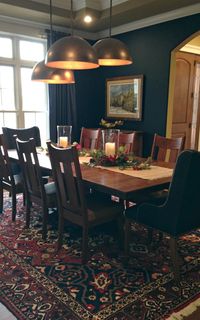 Navy and Red Oriental Rug under custom Dining Room table and chairs. Navy Blue walls. Staggered copper lights.