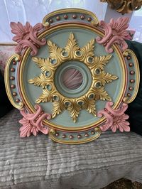 This medallion is ready to ship. A Beautiful and elegant ceiling medallion designed by Shabbyhome. This medallion would look beautiful in a shabby cottage style home. The colors created would be an elegant accent along with your chandelier in a dining room, nursery or bathroom. A Large baroque style ceiling medallion painted in a Sage green and a blush pink. I painted and design this medallion to go with different metals in your chandelier. Other colors are a metallic gold, brilliant copper and silver.  Some use medallions for wall decor, use in a collection of frames, or hang with others or alone, turn this medallion into a wall mirror, just purchase a round mirror that can purchased at most craft stores.  Many uses for the medallions. Ceiling caps are not included.  Most ceiling caps are