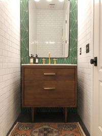 This was a half bath remodel. Polished concrete floors. Floor to ceiling subway tiles with a green sunburst cement tile accent wall. We then added a mid century modern vanity to add warmth to the space.