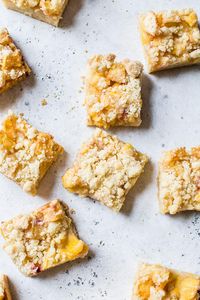 Squares of peach crumb bars on a serving platter.