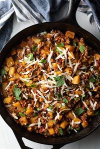 Top down view ground beef and potatoes, topped with shredded parmesan cheese in a skillet.