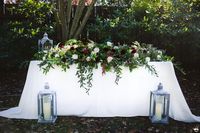 This elegant sweetheart table arrangement was designed for a 6′ table. We made it foliage focused with 5 different kinds of foliage which added rich colors and texture, and movement to the arrangement. The burgundy color looks deep and recessed while the blush colors popped. Burgundy and blush colors are still very popular in today’s wedding.