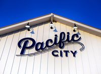 Designed by RSM Design / Architectural Environmental Graphic Design / for Pacific City in Huntington Beach, California. Pacific City. Lighting. Signage and Wayfinding. Wall mural. Public art. Art installation. Surf City. Coastal. Nautical. Outdoor signage design. Storefront sign inspiration. Illuminated sign. Typography inspiration. Outdoor living. Unique retail destination. Explore orange county. Visit orange county. Explore Huntington beach. Design agency.