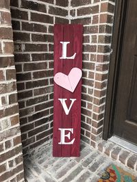 Decorate your porch for Valentines Day with this beautiful LOVE wood sign made from reclaimed wood fence pickets. This rustic porch sign features a red background, white lettering and a hand cut, three dimensional pink wood heart. This sign is just the right touch of warmth to