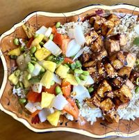 Sweet and Sour Tofu on a platter with brown rice, vegetables and pineapple