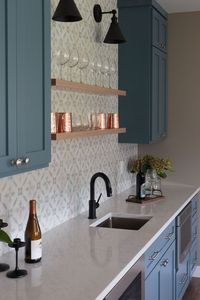 Blue cabinets. White countertops. Black fixtures. Floating shelving. Geometric tile backsplash.