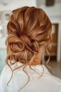 Elegant twisted updo with soft tendrils framing the face, showcasing rich auburn tones perfect for a formal occasion or bridal style. The intricate weaving of strands provides a sophisticated and refined look.  // Photo Credit: Instagram @lisamariehair__