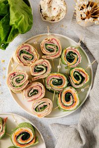 Pinwheel sandwiches are made by spreading flavorful ingredients onto large tortillas, which are then tightly rolled and sliced into spirals.