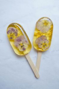 Candy popsicles with pansies and gold leaf. “A fun first way of experimenting with sugar is to get a Silpat mat and some sucker sticks,” says Kristel. “Boil up some sugar syrup to hard crack, pour it onto the Silpat, and add an edible flower on top.”