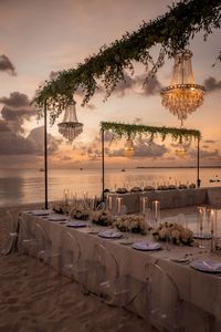 Experience a luxury beach wedding in the Cayman Islands, where timeless elegance meets natural beauty!   Custom-built chandelier structure and lush greenery create a sophisticated atmosphere for this beautiful destination wedding. Clear chairs, lush floral arrangements, and soft candlelight only enhance the timeless appeal of this elegant beach wedding.   Planning a wedding in the Cayman Islands? Let us help you create a unique, one-of-a-kind experience for you and your guests, get in touch with us today ⤵️ https://directionevents.com/contact