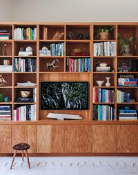 While the lower cabinets hide their son's toys and other unsightly clutter, the shelves artfully display the family's collection of books, trinkets, and of course, their television.