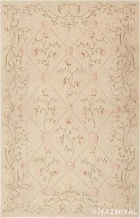 Created in Romania, this recently woven modern rug, elegant Spanish rug design depicts a delicate floral latticework pattern embellished with dainty floral motifs that possess a whimsical, feminine style. The charming latticework pattern showcases delicate floral sprigs decorated with stylized roses that feature spiraling petals. These blushing pink floral emblems mark the intersections of the formal latticework pattern creating a well-coordinated composition.