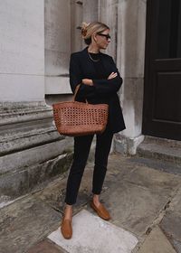 Emma Hill style, Black blazer, Dragon Diffusion tan leather woven tote basket bag, black mom jeans, tan leather loafers, gold jewellery. Chic transitional all black outfit 2020