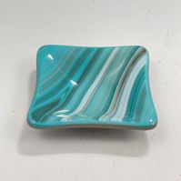 This trinket dish is kilnfired and kilnformed glass. It is the perfect size for many little things such as rings, coins, jewelry, or other items. Its also perfect to hold a teabag or use as a condiment server. Versatile and food safe. Dimensions: 3.25" x 3.25" Do you take your rings off to wash dishes? -- a trinket dish looks great next to the sink and keeps your rings safe. What do you do with your coins when you take them out of your pocket? put your coins in a trinket dish, then its easy to s