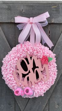 New baby girl wreath for nursery or front door. Made of loop yarn, cute sign and baby socks #babygirlwreath #babywreaths #pinknurserydecor #newbabydecor #babygirlshowergifts #pinklimewreaths