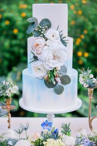 Three tiered light blue watercolor wedding cake, embellished with greenery magnolia leaves and white and blush flowers. // mysweetengagement.com // #wedding #weddingcakes #cakedecorating #cakedesign #weddingideas #weddingdesserts