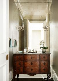 This traditional bathroom with its crown molding and sconces is modernized a bit with a full wall mirror.