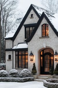 Charming snow-covered brick house with black accents. Create a cozy oasis with simple house designs that offer elegance minus the headache of a mortgage meltdown.