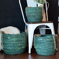 Vibrant dye-soaked green makes these striking baskets breathe the feeling of spring growth and cheery color. Perfect to complement a variety of interiors, let these gathered baskets organize and hold what is needed close at hand with their round chubby bellies. Crafted by hand rope coiled corn husks are woven into gorgeous and durable wicker baskets. Stitched, each basket is reinforced yet flexible to the touch. Rope handles of jute offer contrast with practicality. Expect delightful variations