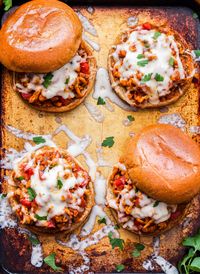 Four Italian Sloppy Joes on a sheet pan. Two are open faced and the other two have the top bun partially off.