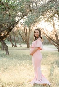 @kellyleevesphotography (IG) capturing beautiful maternity photos in a gorgeous pink, off the shoulder Sexy Mama Maternity gown.  Our Off the Shoulder Maternity Flare Gown is the perfect photoshoot or special event maternity gown! With subtle ruffle detailing, a simple flare, and a premium stretch material this gown is equal parts comfort and elegance.  Maternity shoot. Maternity session. Maternity photography. Maternity photoshoot. Fitted maternity gown. Maternity gown for sale. #maternitygown