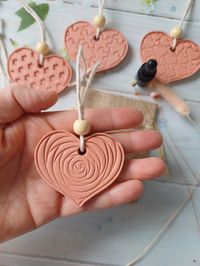 Terracotta Clay Heart with tiny bottle of sample fragrance oil. Drop a couple of drops of oil onto the back of the heart. Please note that the heart may discolour with the oil overtime. A perfect for a New Home, House Warming, Anniversary, Wedding Day or Birthday.  Included in the listing is:- 1 clay heart,  with design options Heart size is 6cm wide by 5m tal 1 tiny sample dropper bottle of fragrance oil with a choice of 3 fragrances. The hearts are hand embossed and completed with natural macr