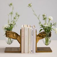 We all need a hand to hold, but especially one designed to hold a bundle of flowers & books. The recycled cast aluminum Handheld Bookend in an antique gold finish features a recycled glass bud vase that's perfect for propagation clippings or a small floral arrangement. With its playful design & sculpture quality, this indoor planter can stand alone, or pair with a second bookend for an attractive bookshelf display. 6in W x 6in D x 8in H Finish: Antique Gold Material: Glass, Metal Set of 2 Made i