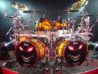 Pearl drums with eerie Halloween jack o'lantern style glowing grin, red eyes, lots of white teeth drum set for band Disturbed with their art on heads.