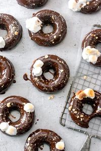 S'mores Donuts - This donut recipe is made lighter and easier with baked donuts! They're dipped in a silky chocolate ganache, and topped with graham cracker crumbs and toasted marshmallows - delish! #donuts #donutrecipe #baking #dessertrecipes #summerrecipes #smores #smoresrecipe #bakingrecipe | bluebowlrecipes.com