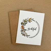 This single folded Thanksgiving card has a fall themed wreath and text that reads, "Grateful" The inside of the card is blank.  Each card purchased comes with one brown Kraft envelope.  Card dimensions: 4.25" wide by 5.5" tall Envelope dimensions: 5.75" wide by 4.375" tall Free shipping is available however tracking is included is not scanned accurately at the time of delivery. If you would like to be able to accurately track your order, please upgrade to either Standard Shipping + Tracking or E