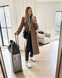 Fashion Jackson Wearing Long Camel Coat Grey Sweater Black AGOLDE Jeans adidas Samba OG Sneakers White Goyard Handbag Loewe Flamenco Handbag Monos Luggage Travel Outfit, travel outfit with sneakers, travel outfit with jeans, winter travel outfit