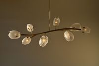 A soft, serpentine silhouette defines this chandelier, dotted with eight Lilia buds. The fixture is crafted from handblown glass petals, each with a soft sandblasted exterior and mirror-polished edge — a nod to the delicate texture of floral arrangements; configuration and color are readily customizable.